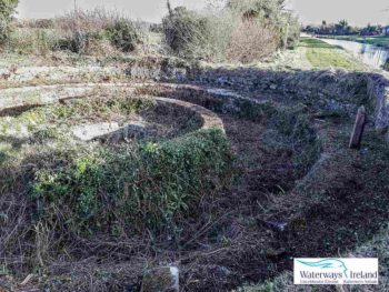 The Four Pots is a unique overflow structure located alongside the Grand Canal towpath between the Leinster Aqueduct and Digby Bridge. No longer in use, this ingenious overflow system has four circular channels of varying depth that helped reduce the water pressure and volume rate before discharge from the canal back to the River Liffey through a series of channels. All built heritage features throughout our waterways have been documented by Waterways Ireland and can be accessed.

Die Four Pots sind ein einzigartiges Überlaufbauwerk, das sich entlang des Treidelpfades des Grand Canal zwischen dem Leinster Aqueduct und der Digby Bridge befindet. Dieses ausgeklügelte Überlaufsystem mit vier kreisförmigen Kanälen unterschiedlicher Tiefe, das nicht mehr in Betrieb ist, trug dazu bei, den Wasserdruck und die Wassermenge zu verringern, bevor es über eine Reihe von Kanälen wieder in den Fluss Liffey abgelassen wurde. Alle Baudenkmäler entlang unserer Wasserstraßen wurden von Waterways Ireland dokumentiert und können eingesehen werden.